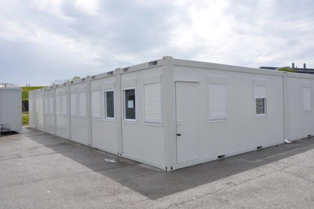 A row of white modular buildings with shutters on the windows.