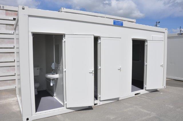 White modular building with multiple doors open, revealing bathroom facilities inside