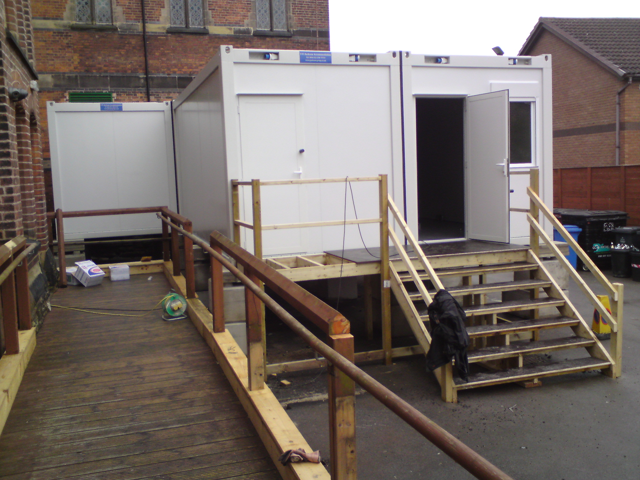 Wooden walkways and railings leading up to modular units in an outdoor setting